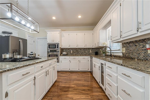 kitchen with a sink, appliances with stainless steel finishes, crown molding, and white cabinetry