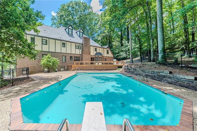 view of swimming pool featuring a fenced in pool, a diving board, fence private yard, and a deck