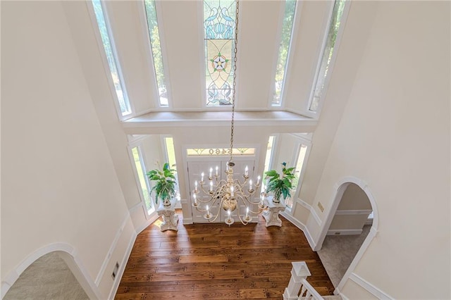 entrance foyer with dark wood-type flooring, a towering ceiling, and a notable chandelier