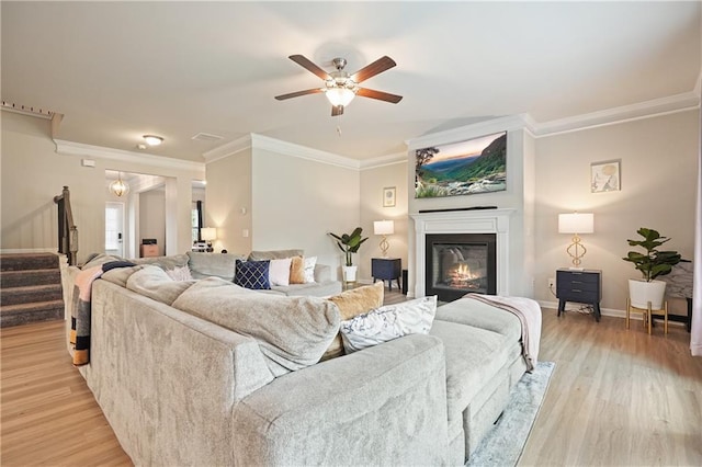 5322 Burrus Ln SW, Mableton, GA 30126 - living area with stairs, crown molding, a glass covered fireplace, light wood-style floors, and ceiling fan