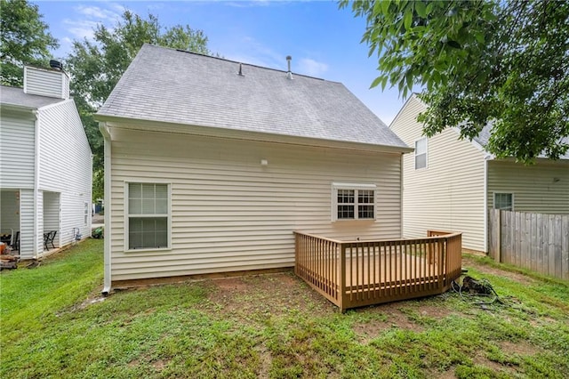 rear view of house with a wooden deck and a lawn