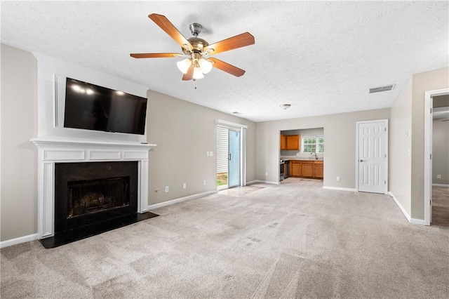 unfurnished living room featuring sink, light carpet, ceiling fan, and a textured ceiling