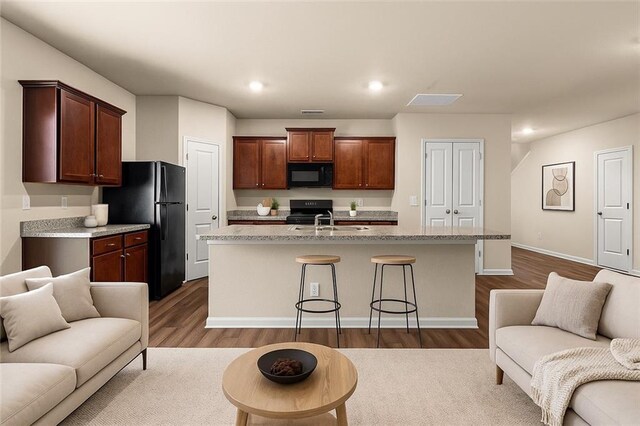 10786 Wheeler Trce, Hampton, GA 30228 - kitchen featuring black appliances, open floor plan, light countertops, a center island with sink, and recessed lighting