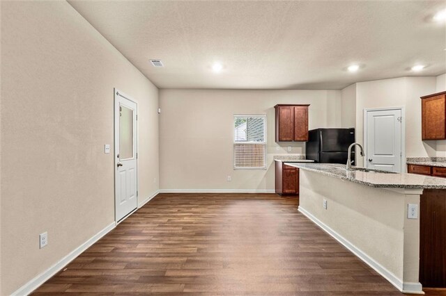 10786 Wheeler Trce, Hampton, GA 30228 - kitchen featuring freestanding refrigerator, a sink, dark wood-style flooring, an island with sink, and light stone countertops