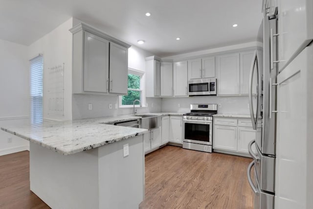 11280 Brookhollow Trl, Alpharetta, GA 30022 - kitchen featuring appliances with stainless steel finishes, a peninsula, a sink, light stone counters, and decorative backsplash
