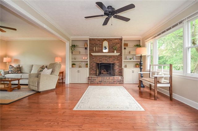 living area with baseboards, a ceiling fan, a healthy amount of sunlight, and light wood-type flooring