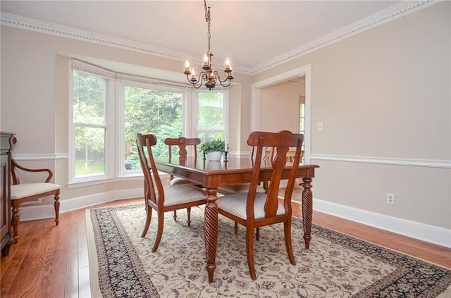 dining room featuring crown molding, baseboards, light wood-type flooring, and a chandelier