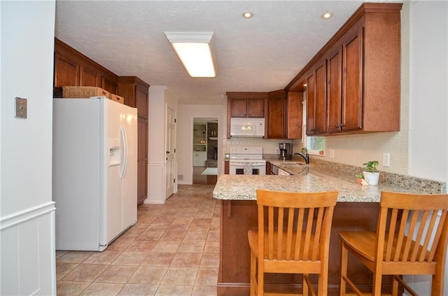 kitchen with white appliances, a peninsula, a textured ceiling, and a sink