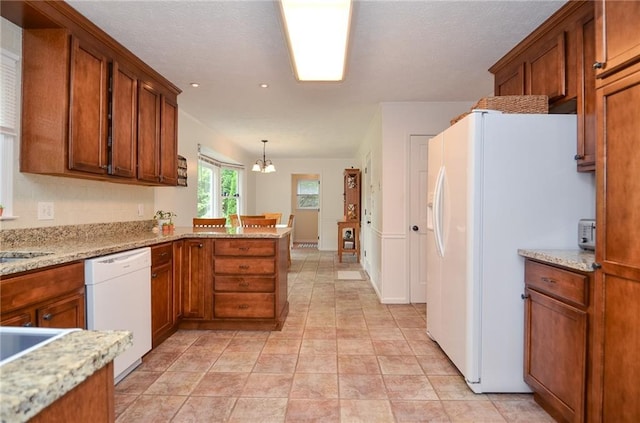 kitchen with brown cabinets, an inviting chandelier, hanging light fixtures, white appliances, and a peninsula