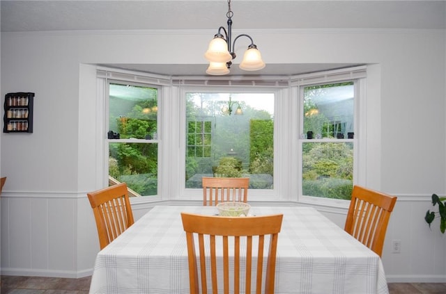 dining space with a wainscoted wall, ornamental molding, a decorative wall, and a chandelier