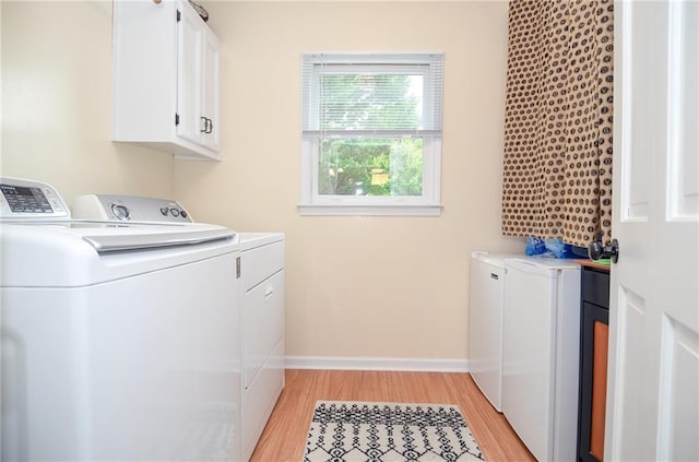laundry room featuring baseboards, light wood-style flooring, cabinet space, and independent washer and dryer