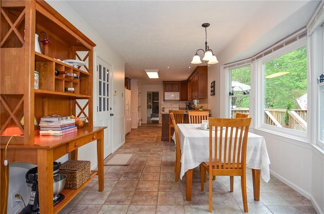 dining room featuring an inviting chandelier, stone finish flooring, and baseboards