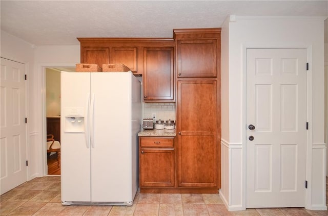 kitchen featuring decorative backsplash, white fridge with ice dispenser, brown cabinets, and a textured ceiling