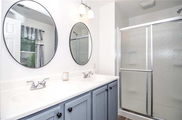 bathroom with double vanity, visible vents, a shower stall, and a sink
