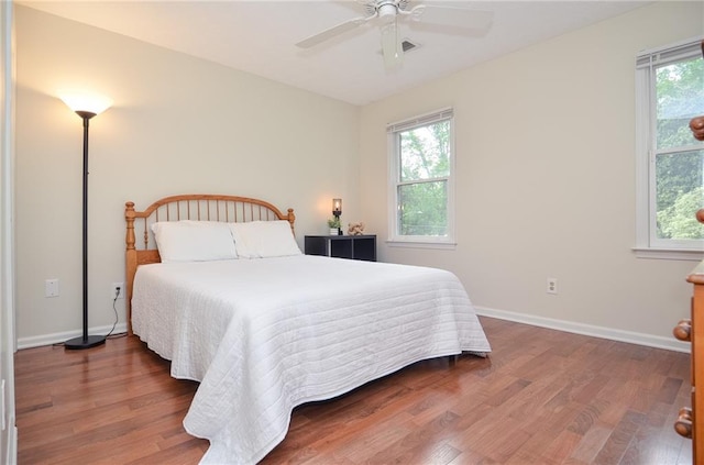 bedroom featuring baseboards, wood finished floors, and multiple windows