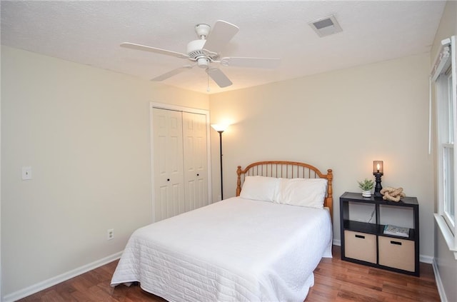 bedroom with baseboards, visible vents, wood finished floors, and a closet