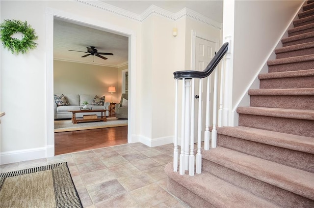 staircase with crown molding, a ceiling fan, and baseboards