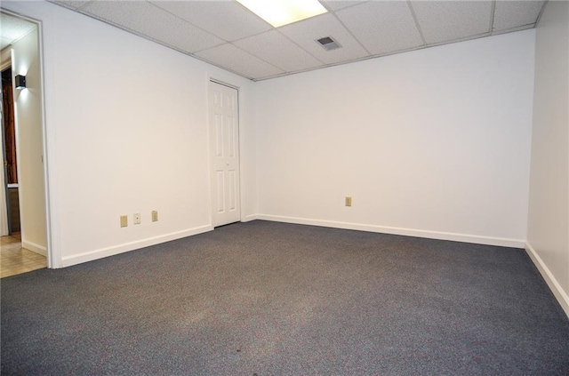 carpeted spare room with visible vents, baseboards, and a drop ceiling