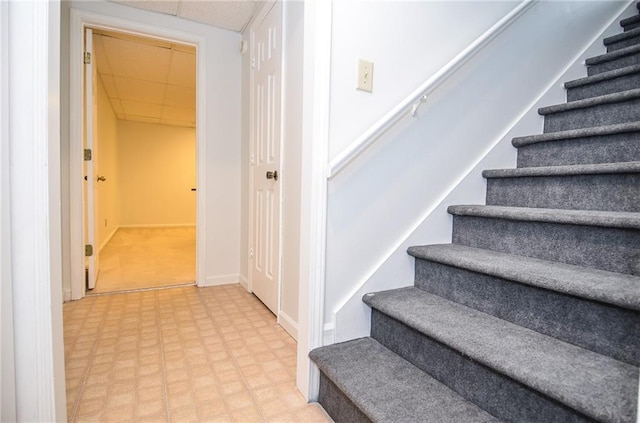 stairway with tile patterned floors, baseboards, and a paneled ceiling