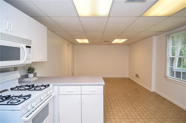 kitchen featuring a peninsula, white appliances, light countertops, a paneled ceiling, and white cabinetry