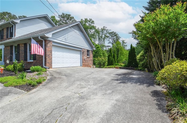 view of property exterior featuring brick siding, an attached garage, and driveway