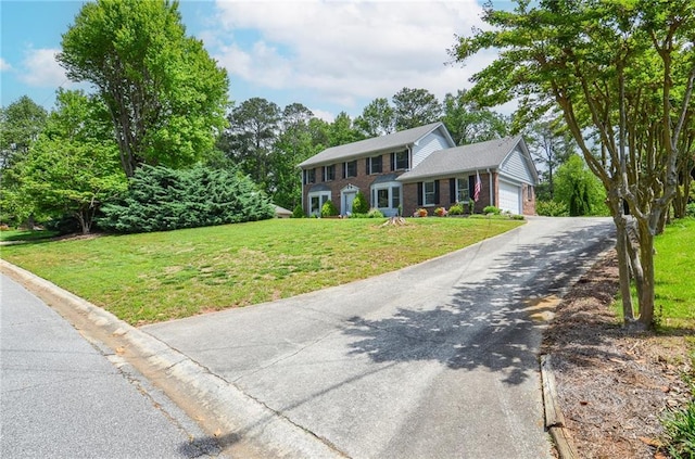 colonial inspired home featuring brick siding, a garage, a front lawn, and aphalt driveway