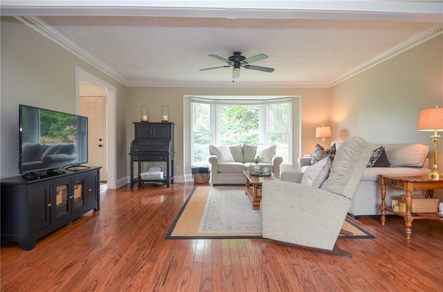 living area with a ceiling fan, baseboards, ornamental molding, and wood finished floors