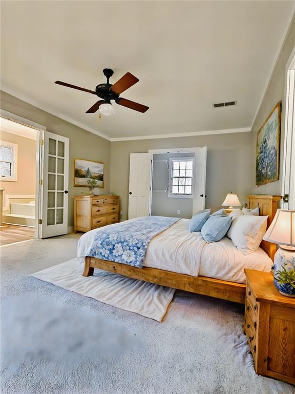 bedroom featuring french doors, ensuite bathroom, ceiling fan, and crown molding