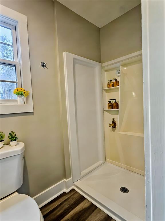 bathroom featuring a shower, hardwood / wood-style floors, and toilet