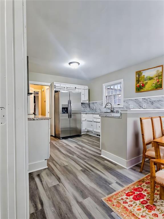 kitchen featuring white cabinets, sink, dark hardwood / wood-style floors, stainless steel fridge, and decorative backsplash