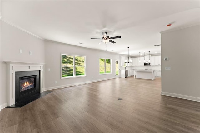 418 Brookstone Trl, Dawsonville, GA 30534 - unfurnished living room with ceiling fan, baseboards, a glass covered fireplace, ornamental molding, and dark wood-style flooring