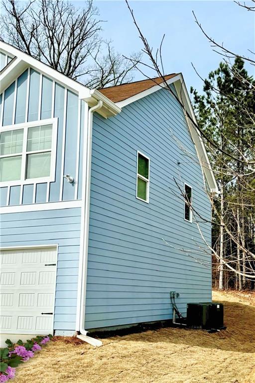 view of side of home with a garage and central air condition unit