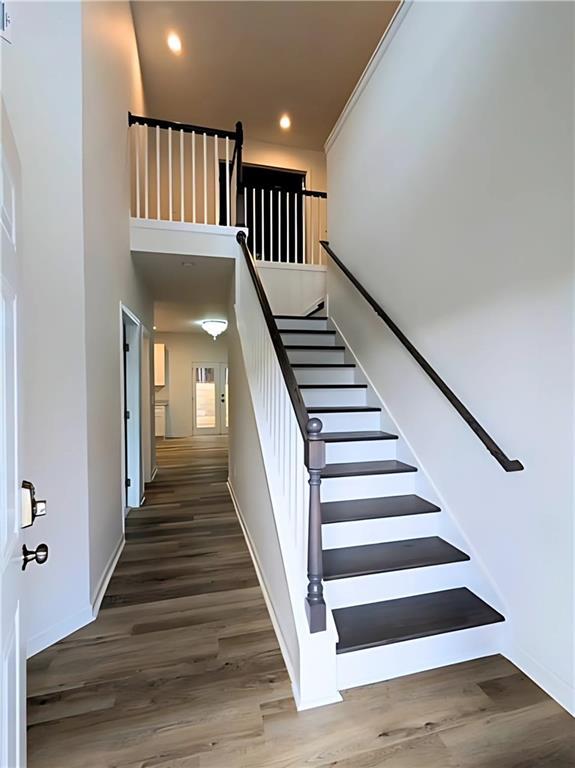 stairs featuring hardwood / wood-style flooring and a high ceiling