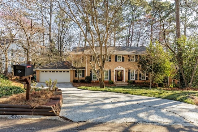 colonial house with driveway, an attached garage, and a front lawn