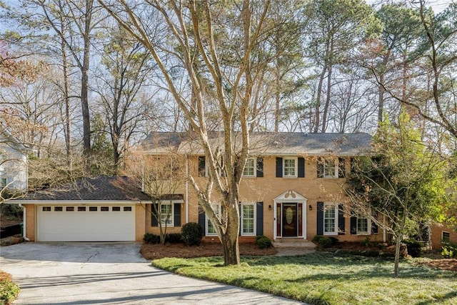 colonial house with a front lawn, an attached garage, and driveway