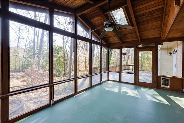 unfurnished sunroom featuring vaulted ceiling with skylight, wooden ceiling, and a ceiling fan