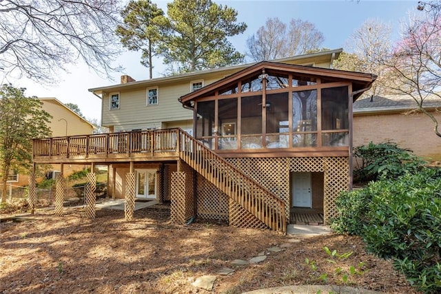 back of house featuring a wooden deck, stairs, french doors, a chimney, and a sunroom