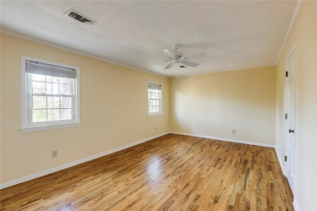 spare room with visible vents, ornamental molding, light wood-style floors, baseboards, and ceiling fan