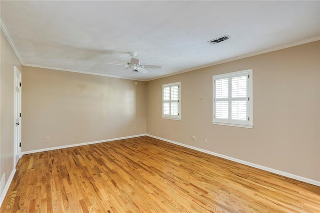 empty room with crown molding, baseboards, and light wood finished floors