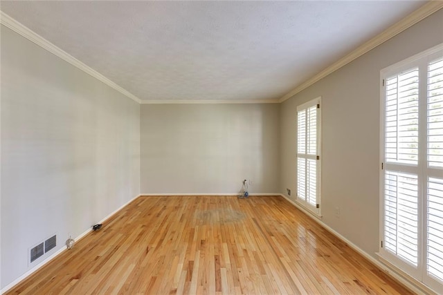 unfurnished room with visible vents, baseboards, light wood-style floors, and ornamental molding