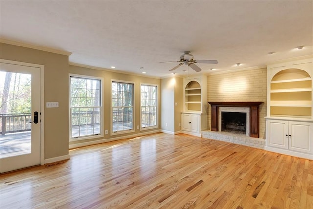 unfurnished living room with light wood finished floors, built in features, a fireplace, and ornamental molding