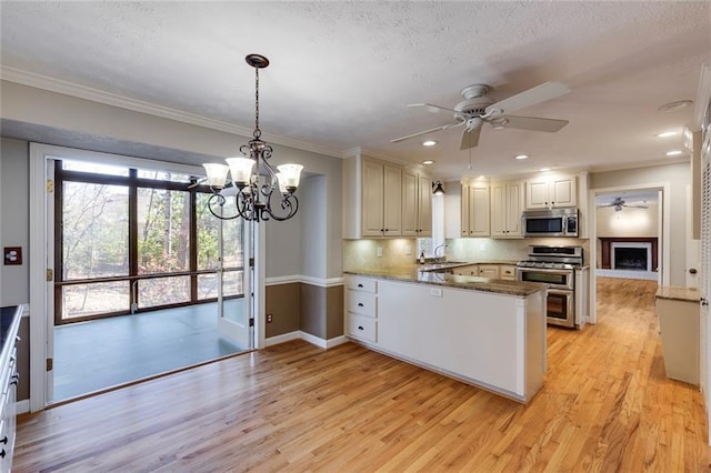 kitchen with light wood-style flooring, a sink, stainless steel appliances, ceiling fan with notable chandelier, and backsplash