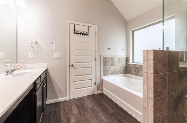 bathroom with vanity, vaulted ceiling, hardwood / wood-style floors, and a bathing tub