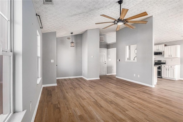 unfurnished living room featuring baseboards, a ceiling fan, and light wood-style floors