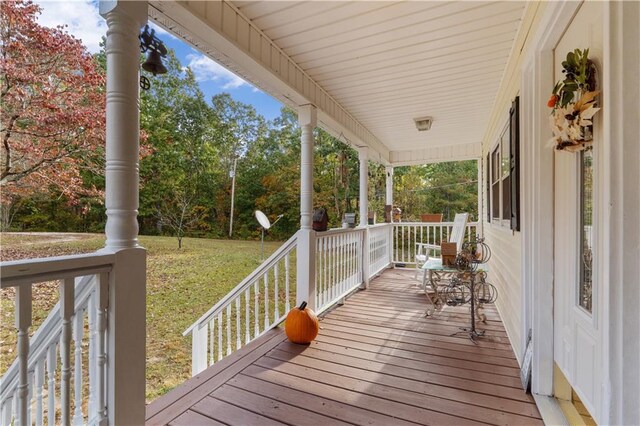 wooden terrace featuring a porch and a lawn