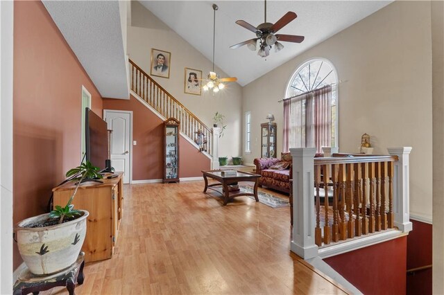 entryway with ceiling fan, high vaulted ceiling, and light hardwood / wood-style flooring