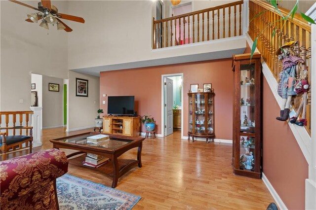 living room with ceiling fan, wood-type flooring, and a high ceiling