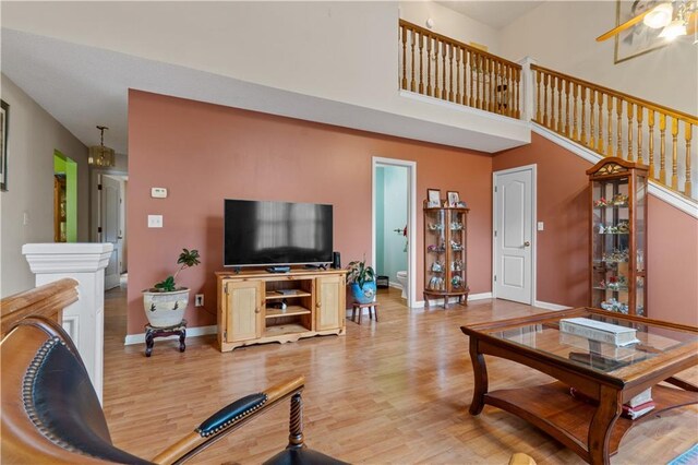 living room featuring light hardwood / wood-style flooring and ceiling fan with notable chandelier