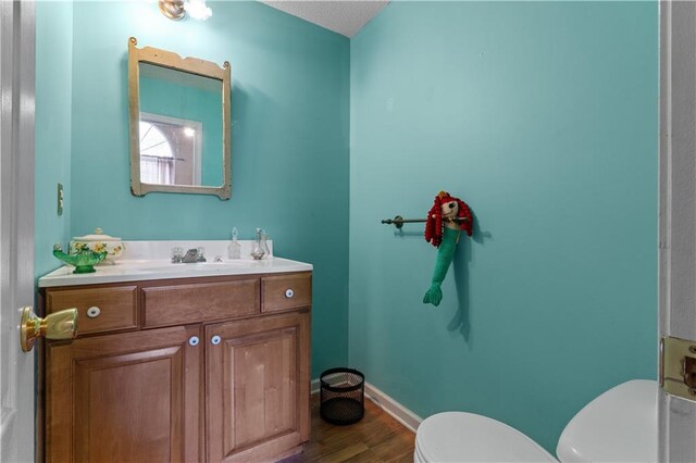 bathroom featuring vanity, a textured ceiling, wood-type flooring, and toilet