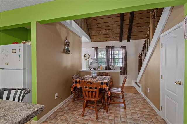 dining space with lofted ceiling with beams and light tile patterned floors